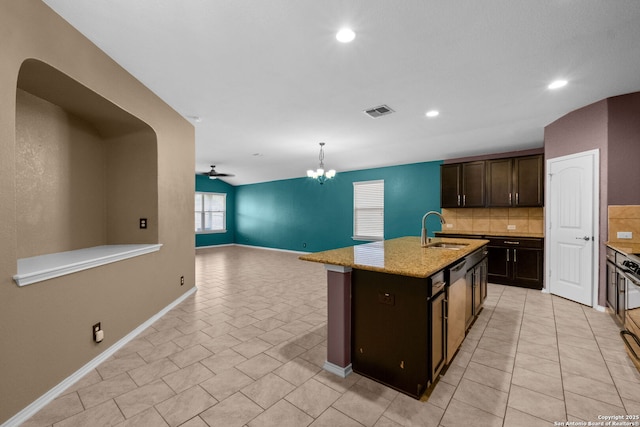 kitchen featuring sink, dark brown cabinets, pendant lighting, a kitchen island with sink, and backsplash