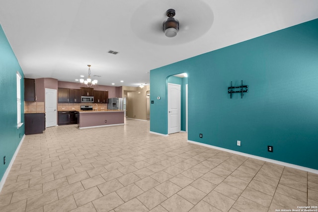 unfurnished living room with ceiling fan with notable chandelier and light tile patterned floors