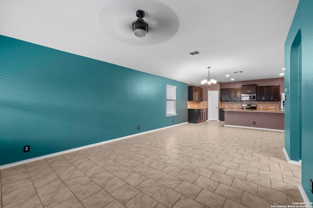 unfurnished living room featuring ceiling fan with notable chandelier