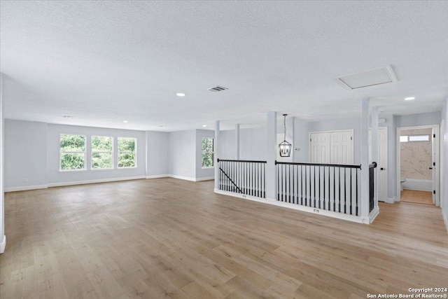 empty room with a textured ceiling and light hardwood / wood-style floors