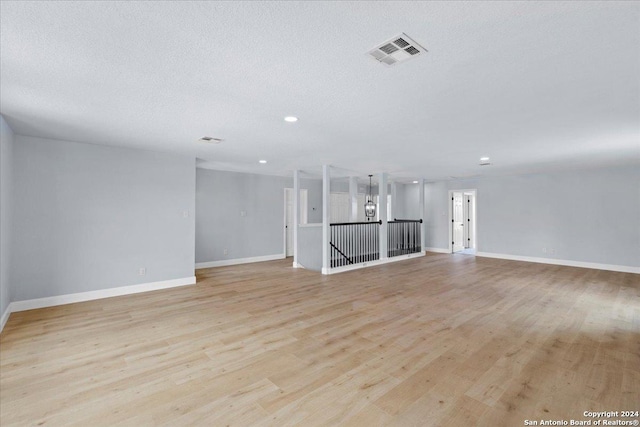 unfurnished living room with a textured ceiling and light wood-type flooring