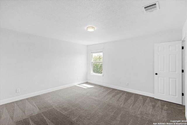 unfurnished room with a textured ceiling and carpet flooring