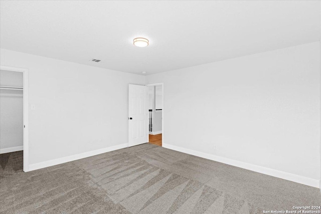 unfurnished bedroom with a spacious closet, carpet floors, and a closet