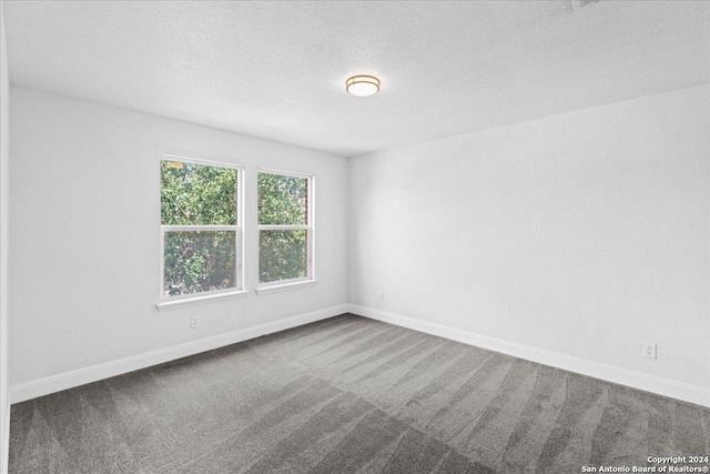 carpeted empty room featuring a textured ceiling