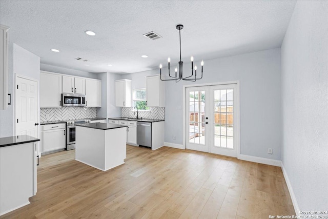 kitchen featuring sink, hanging light fixtures, stainless steel appliances, white cabinets, and french doors