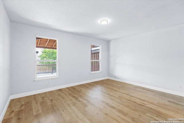 unfurnished room with a textured ceiling and light wood-type flooring