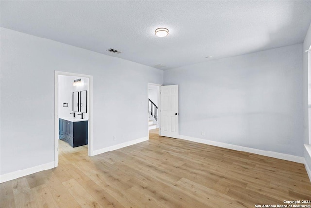 spare room with light hardwood / wood-style flooring and a textured ceiling