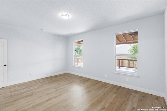 unfurnished room with a textured ceiling and light wood-type flooring