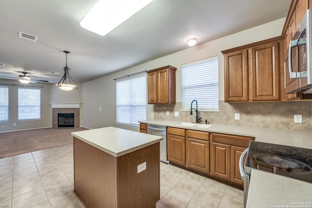 kitchen featuring a tile fireplace, appliances with stainless steel finishes, pendant lighting, sink, and a center island