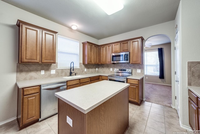 kitchen with backsplash, stainless steel appliances, sink, and a kitchen island