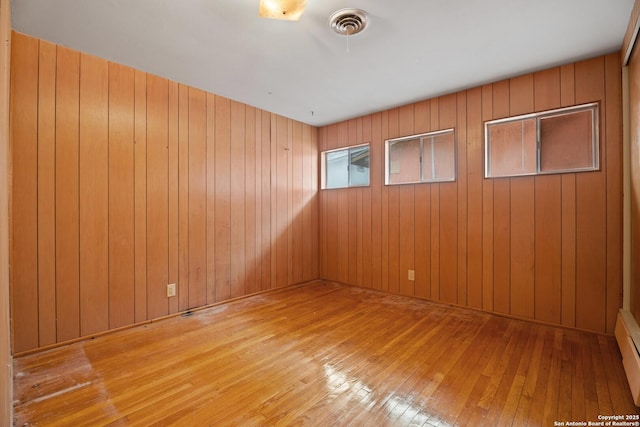 unfurnished room featuring light hardwood / wood-style floors and wood walls