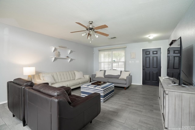 living room with ceiling fan and a textured ceiling