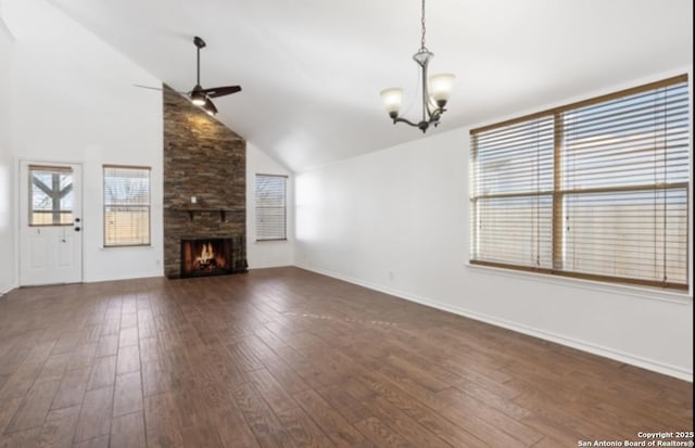 unfurnished living room featuring dark wood-type flooring, high vaulted ceiling, a fireplace, and ceiling fan with notable chandelier