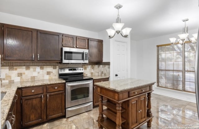 kitchen featuring light stone counters, a notable chandelier, hanging light fixtures, and appliances with stainless steel finishes