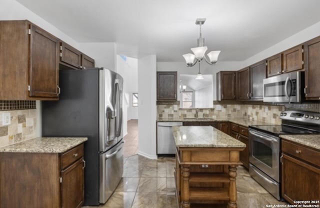 kitchen with appliances with stainless steel finishes, tasteful backsplash, sink, a center island, and dark brown cabinets