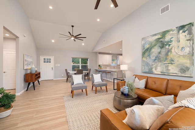 living room featuring high vaulted ceiling, ceiling fan, and light wood-type flooring