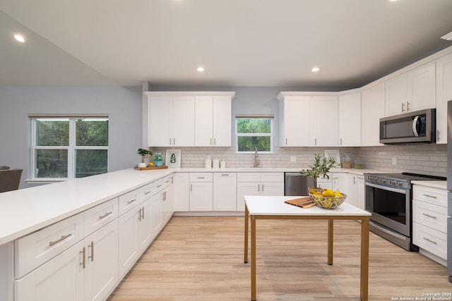 kitchen with sink, stainless steel appliances, kitchen peninsula, and white cabinets