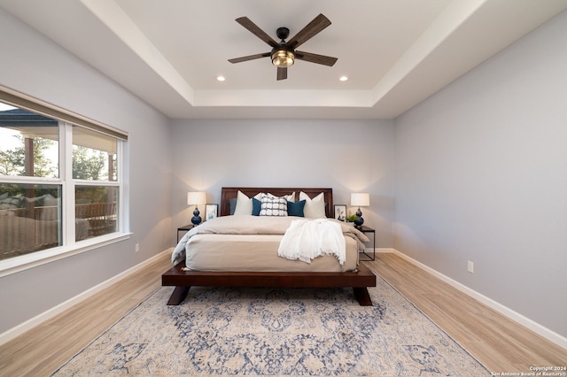 bedroom featuring a tray ceiling, hardwood / wood-style flooring, and ceiling fan