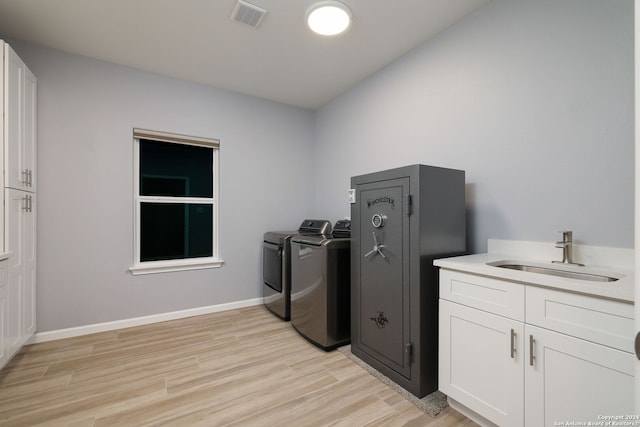 washroom with cabinets, washer and clothes dryer, sink, and light wood-type flooring