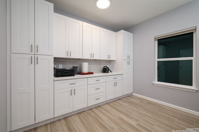 kitchen with white cabinetry, decorative backsplash, and light hardwood / wood-style flooring