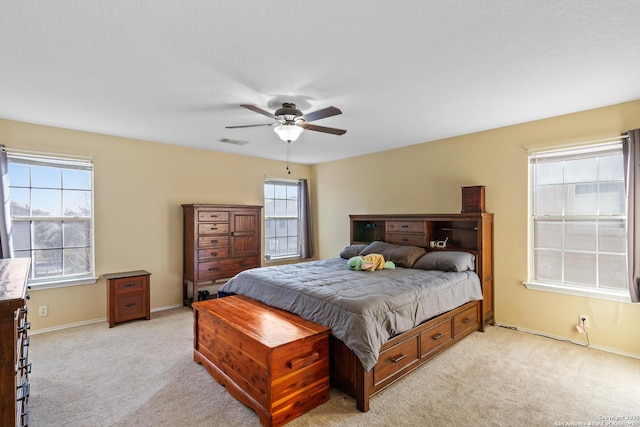 bedroom with baseboards, visible vents, a ceiling fan, and light colored carpet