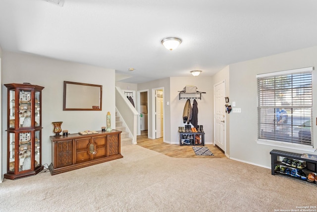 entrance foyer with light carpet, baseboards, and stairs