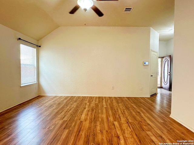 empty room with vaulted ceiling, ceiling fan, and light hardwood / wood-style flooring