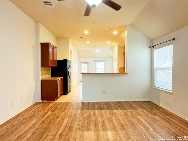 kitchen featuring lofted ceiling, decorative backsplash, ceiling fan, black fridge with ice dispenser, and light hardwood / wood-style flooring