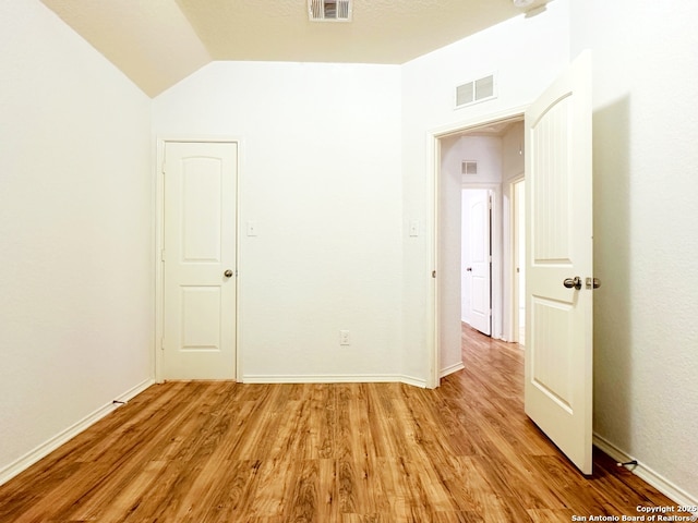 empty room with lofted ceiling and light wood-type flooring