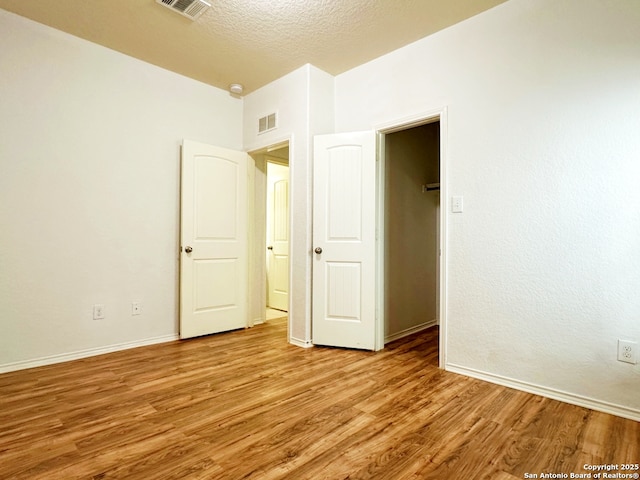 spare room with a textured ceiling and light wood-type flooring