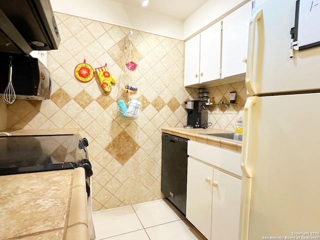 kitchen with light tile patterned floors, dishwasher, backsplash, white cabinets, and white fridge