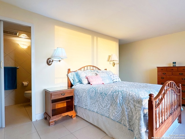 bedroom with ensuite bath and light tile patterned floors