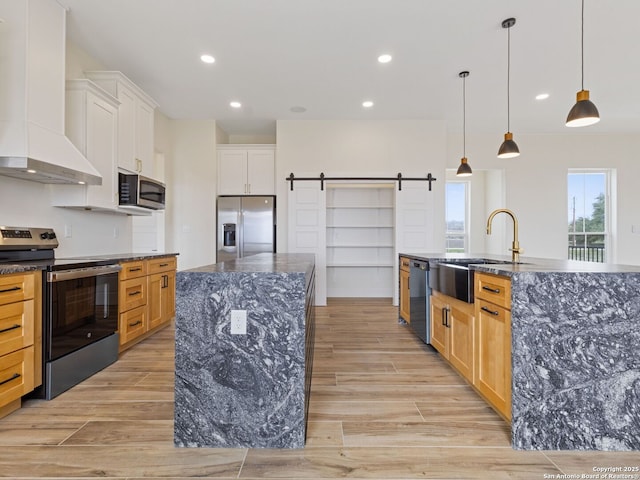 kitchen with custom exhaust hood, white cabinetry, a barn door, appliances with stainless steel finishes, and a large island