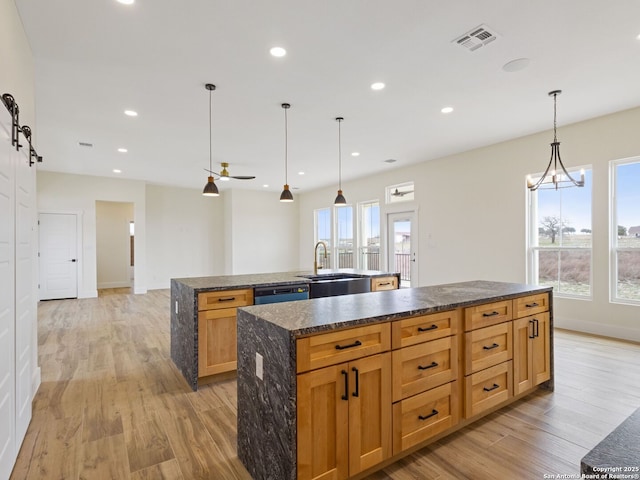 kitchen with pendant lighting, sink, a spacious island, light hardwood / wood-style floors, and a barn door