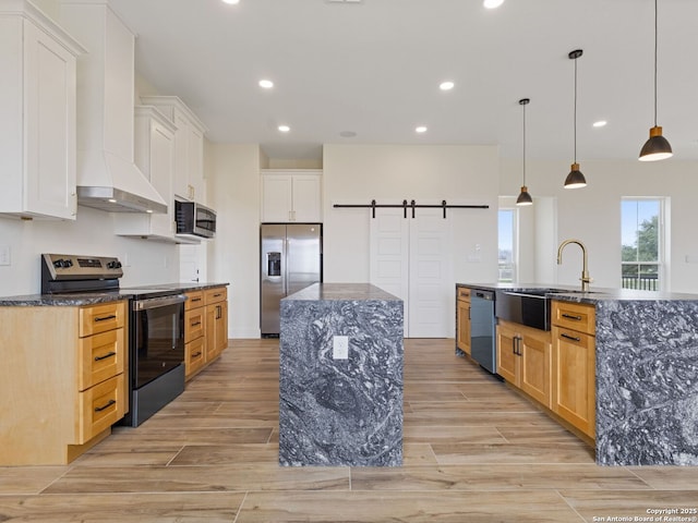 kitchen with pendant lighting, stainless steel appliances, white cabinets, a barn door, and a large island with sink