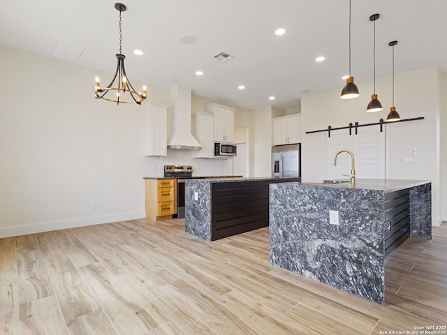 kitchen with appliances with stainless steel finishes, white cabinetry, a spacious island, custom range hood, and a barn door