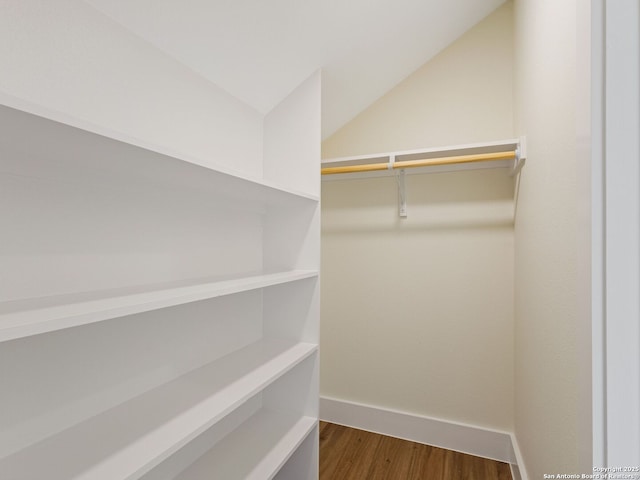 walk in closet with vaulted ceiling and hardwood / wood-style floors