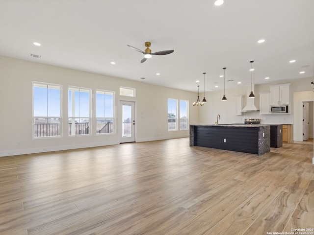 unfurnished living room with ceiling fan, light hardwood / wood-style floors, and sink