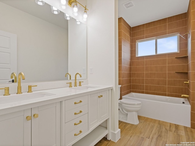 full bathroom with hardwood / wood-style flooring, vanity, toilet, and tiled shower / bath combo