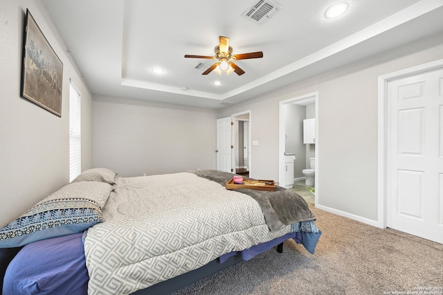 carpeted bedroom with ceiling fan, connected bathroom, and a tray ceiling