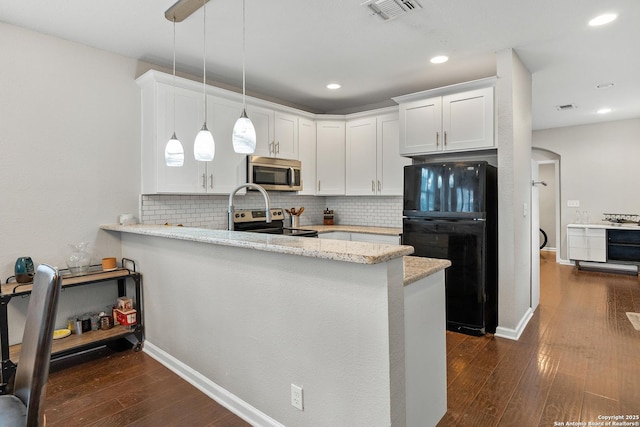 kitchen with appliances with stainless steel finishes, white cabinetry, light stone counters, decorative light fixtures, and kitchen peninsula