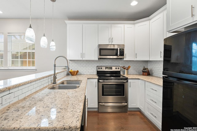 kitchen featuring appliances with stainless steel finishes, sink, white cabinets, and decorative light fixtures