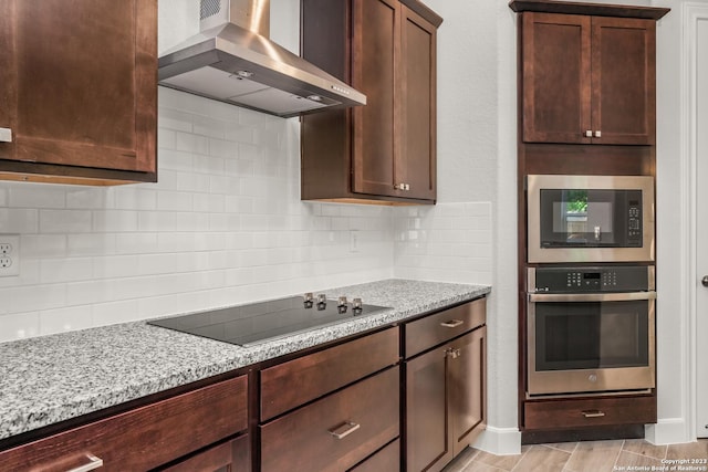 kitchen featuring built in microwave, extractor fan, black electric cooktop, light stone countertops, and oven