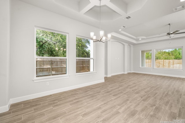 empty room featuring light hardwood / wood-style flooring, ceiling fan with notable chandelier, a wealth of natural light, and coffered ceiling