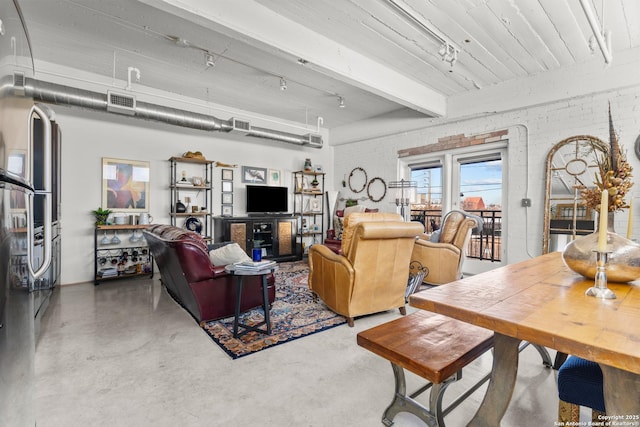 living room featuring brick wall, beam ceiling, and concrete floors