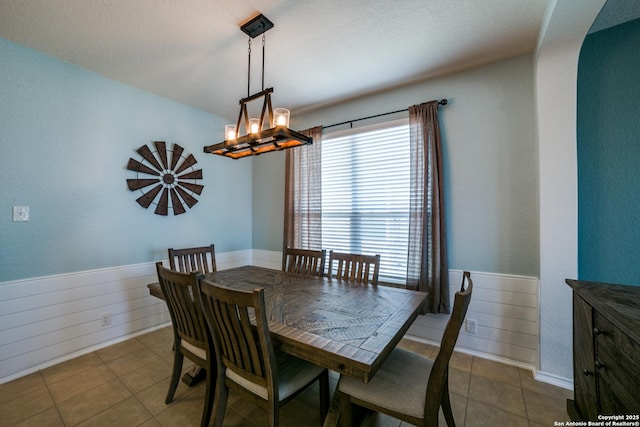 dining space with an inviting chandelier and wood walls