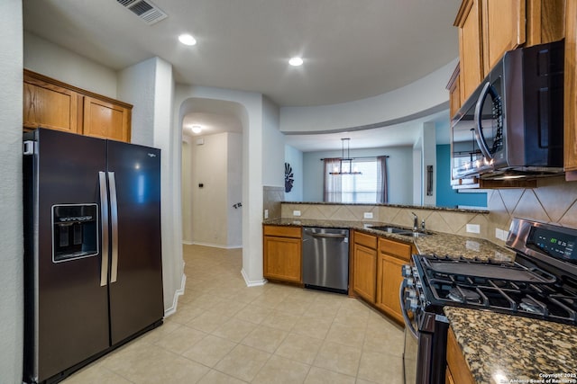 kitchen featuring sink, decorative light fixtures, dark stone countertops, stainless steel appliances, and backsplash