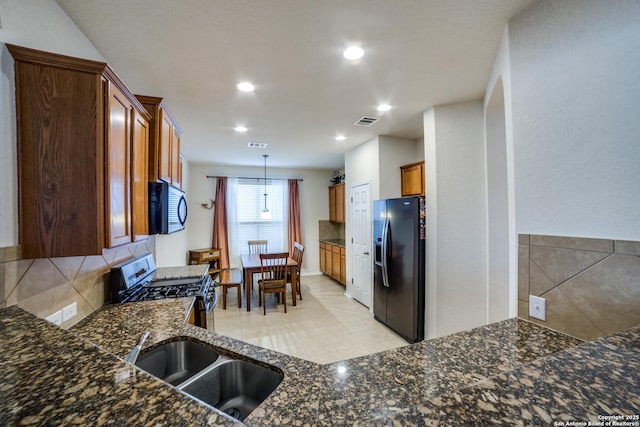 kitchen with black fridge, gas stove, decorative backsplash, and pendant lighting