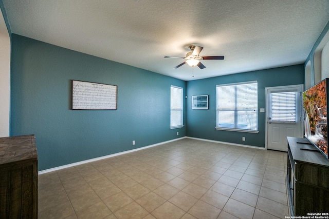 tiled spare room featuring a textured ceiling and ceiling fan