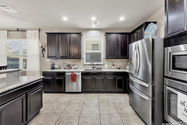 kitchen featuring dark brown cabinetry, sink, tasteful backsplash, and stainless steel appliances